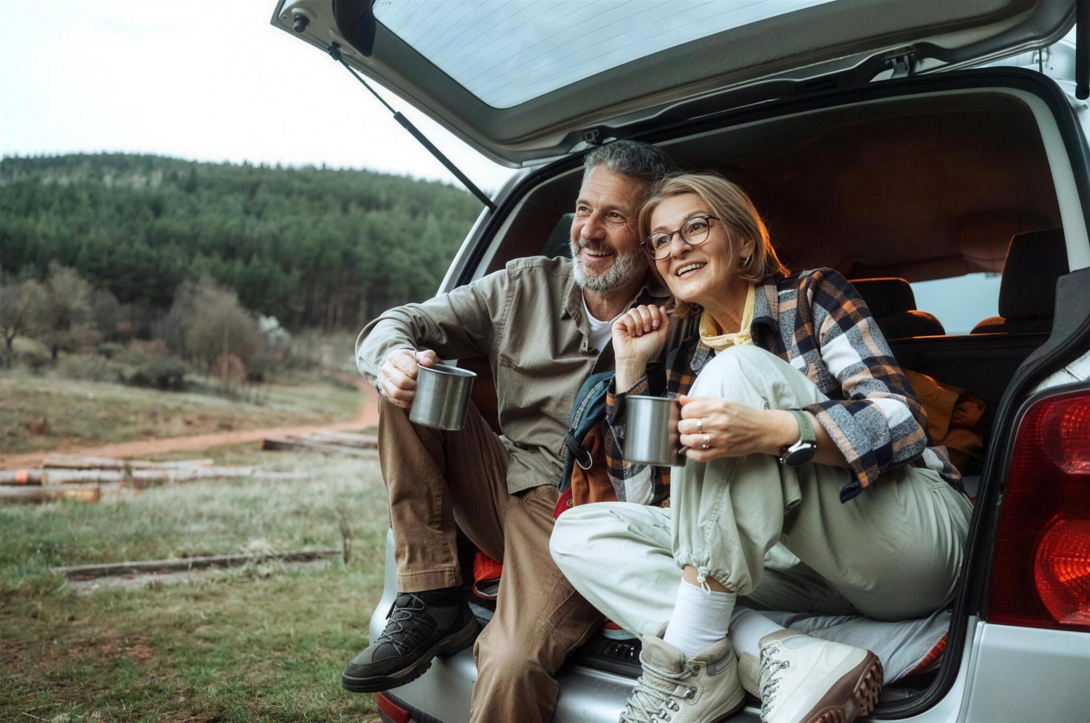 Couple in their sixties sharing a hot drink in the back of their car